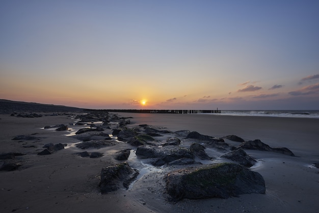 Schöne Aussicht auf den Sonnenuntergang mit lila Wolken über dem Strand