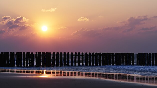 Schöne Aussicht auf den Sonnenuntergang mit lila Wolken über dem Strand