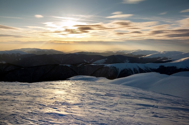 Schöne bergsonnenunterganglandschaft mit sonnenweg am vereisten berghang. (ukraine, karpaten, svydovets range)