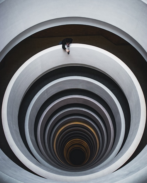 Schöne Überkopfaufnahme einer Wendeltreppe mit einem Fotografen, der eine Aufnahme von der Öffnung macht