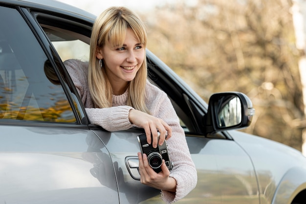 Schöne blonde Frau, die eine Weinlesekamera anhält