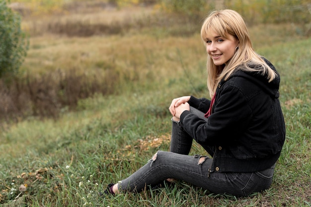 Schöne blonde Frau, die in der Natur sitzt