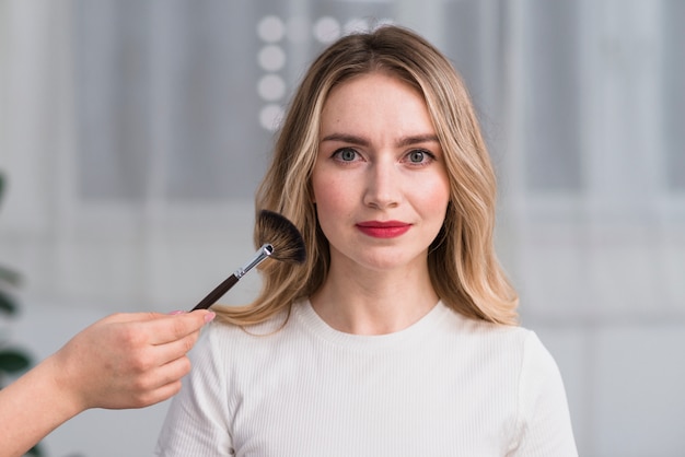 Schöne blonde Frau, die Make-up im Schönheitssalon hat