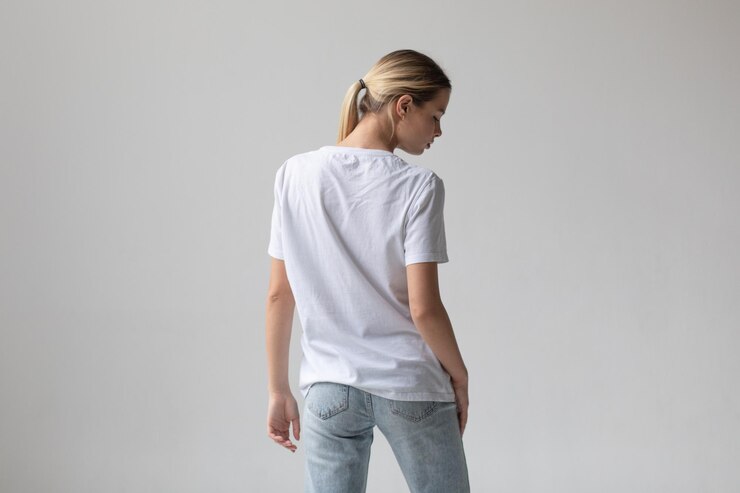Schöne blonde Frau in einem weißen T-Shirt und blauen Jeans posiert auf einem weißen Hintergrund