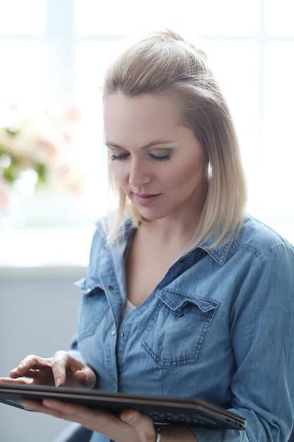 Schöne blonde Frau mit digitaler Tablette