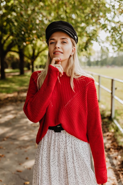 Schöne Blondine mit natürlichem Make-up, das zärtlich aussieht. Hübsches Modell im schönen Kleid, das auf dem Waldweg aufwirft.