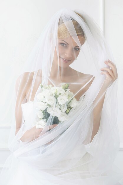 Schöne Braut mit Schleier und Blumenstrauß