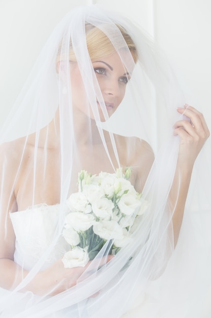 Schöne Braut mit Schleier und Blumenstrauß