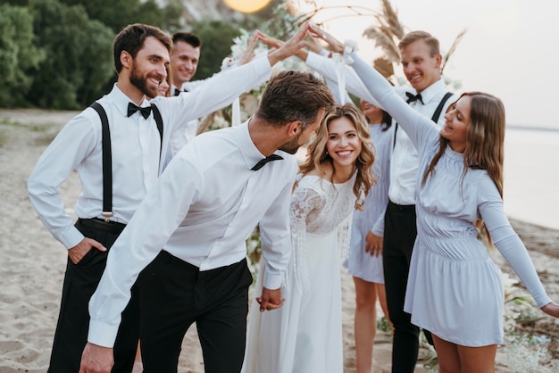 Kostenloses Foto schöne braut und bräutigam, die ihre hochzeit mit gästen am strand haben