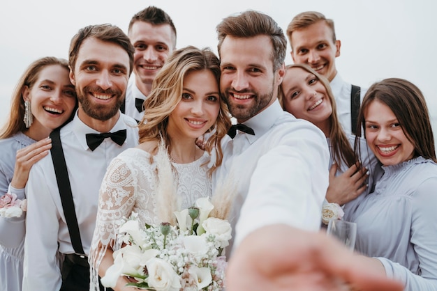 Schöne Braut und Bräutigam, die ihre Hochzeit mit Gästen am Strand haben