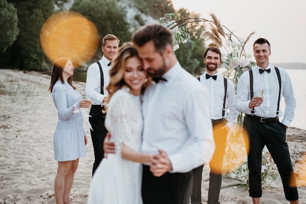 Schöne Braut und Bräutigam haben ihre Hochzeit mit Gästen am Strand
