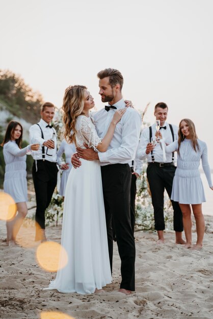 Schöne Braut und Bräutigam haben ihre Hochzeit mit Gästen am Strand