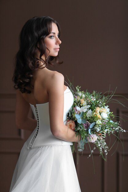 Schöne Brautfrau im eleganten Hochzeitskleid mit Blumenstrauß