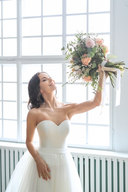 Schöne brautfrau im eleganten hochzeitskleid mit blumenstrauß