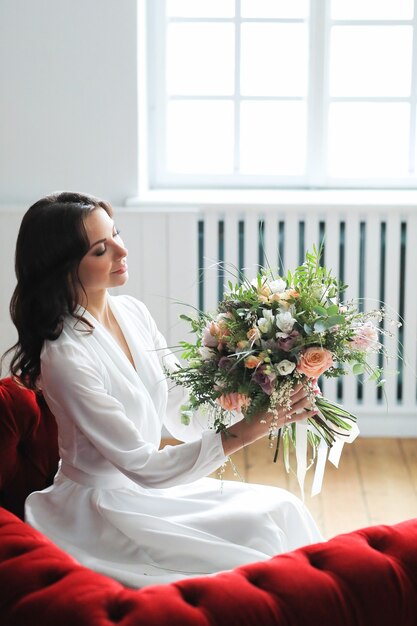 Schöne Brautfrau im eleganten Hochzeitskleid mit Blumenstrauß