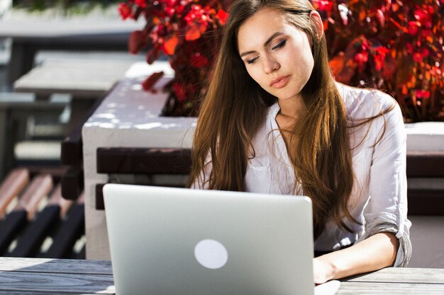 Schöne Brünette arbeitet mit Laptop draußen