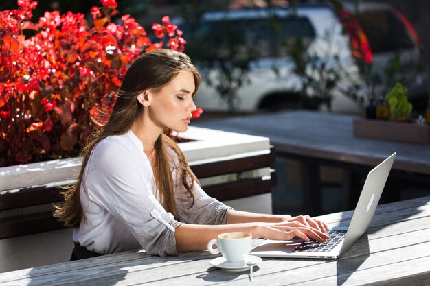 Schöne Brünette arbeitet mit Laptop draußen