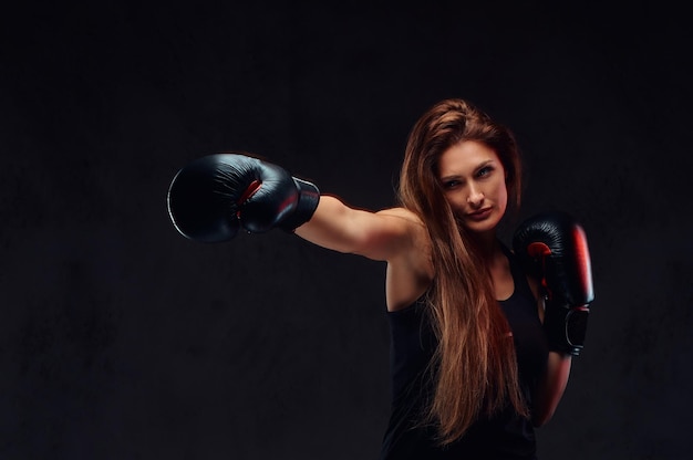 Schöne brünette Boxerin bei Boxübungen, konzentriert auf den Prozess mit ernsthafter, konzentrierter Gesichtsbehandlung.