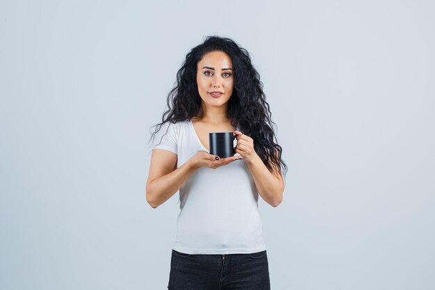 Schöne brünette Frau, die einen Becher hält