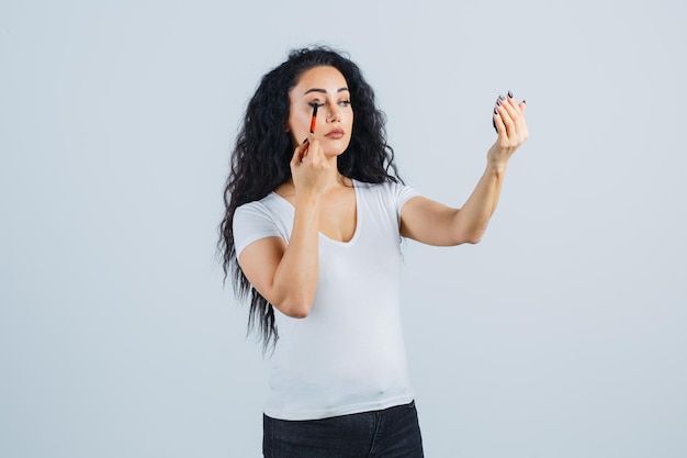 Schöne brünette Frau, die Make-up aufträgt