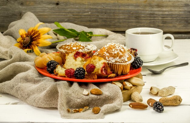 schöne Cupcakes mit Beeren auf Holzwand in roter Platte