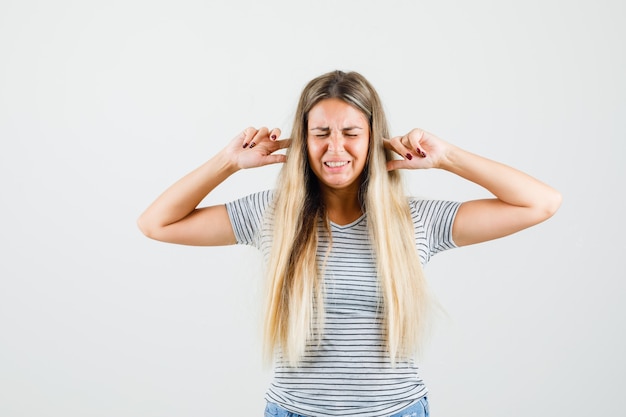 Kostenloses Foto schöne dame, die ihre ohren in t-shirt einsteckt und stressig aussieht, vorderansicht.