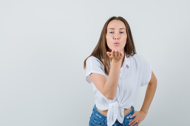 Schöne Dame, die Luftkuss in der weißen Bluse sendet und geliebt schaut. Vorderansicht. Platz für Text