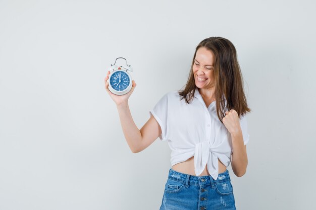 Schöne Dame in der weißen Bluse, die Uhr schaut und lustig schaut, Vorderansicht.