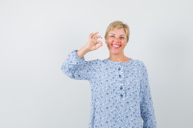 Kostenloses Foto schöne dame in gemusterter bluse, die ok geste zeigt und fröhlich, vorderansicht schaut.