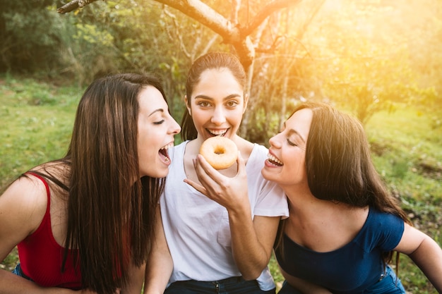 Schöne Damen, die Donut teilen