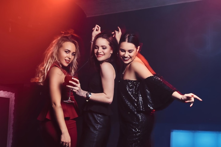 Kostenlose Foto schöne, elegant gekleidete freundinnen amüsieren sich im nachtclub und tanzen mit alkohol auf der tanzfläche.