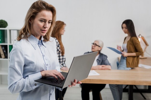 Schöne erwachsene Frau, die einen Laptop durchstöbert