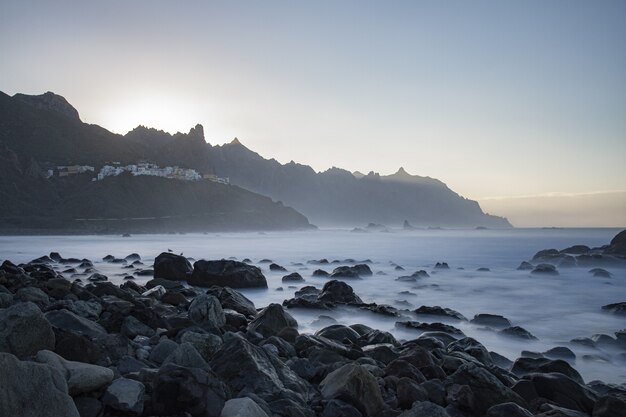 Schöne Felsen am Strand am nebligen Meer mit den Bergen