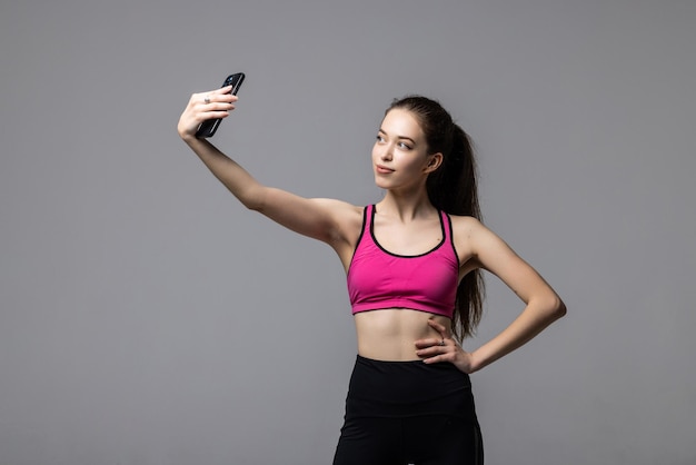 Schöne Fitness-Frau macht Selfie-Foto auf einem weißen