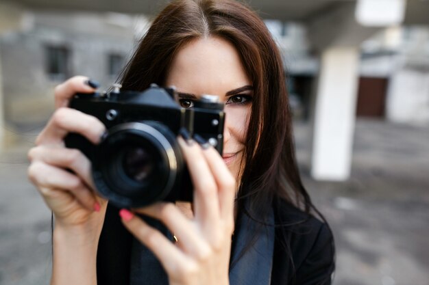 Schöne Fotografin, die mit Kamera aufwirft