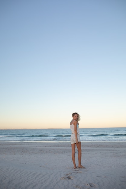 Schöne frau am strand stehen