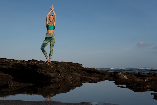 Kostenloses Foto schöne frau beim yoga am strand