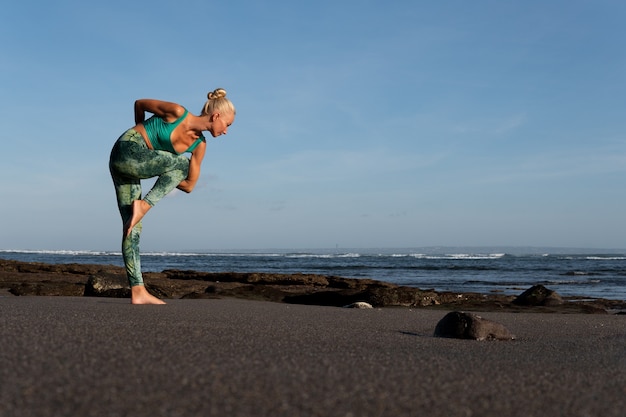 Kostenloses Foto schöne frau beim yoga am strand