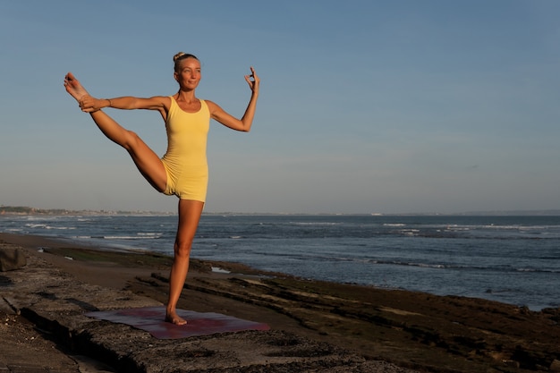 Schöne frau beim yoga am strand