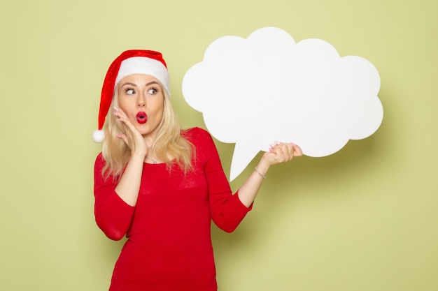 Schöne Frau der Vorderansicht, die großes weißes Zeichen auf der grünen Wand Weihnachten Schnee Foto Urlaub Emotion neues Jahr hält