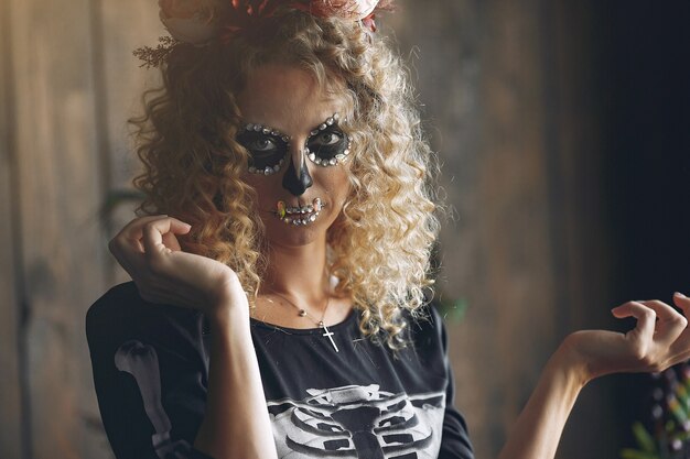 Schöne Frau des Halloween-Schminkschädels mit blonder Frisur. Santa Muerte Model Girl im schwarzen Kostüm.