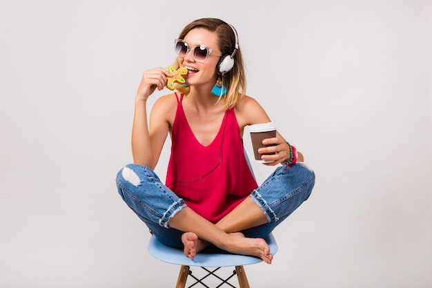 Schöne Frau des jungen Hipsters, die im Stuhl sitzt und Kekse isst