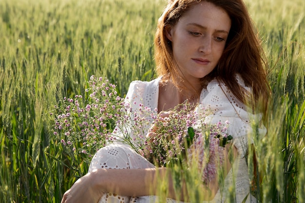 Kostenloses Foto schöne frau des mittleren schusses, die auf gras legt