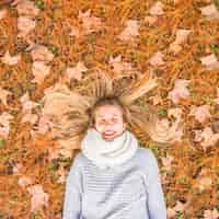 Kostenloses Foto schöne frau, die auf herbstboden legt