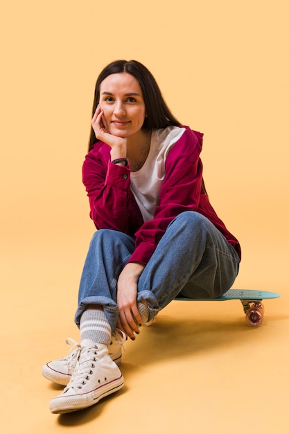 Schöne Frau, die auf Skateboard sitzt