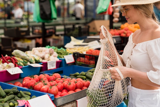 Schöne Frau, die Bio-Tasche für Gemüse verwendet