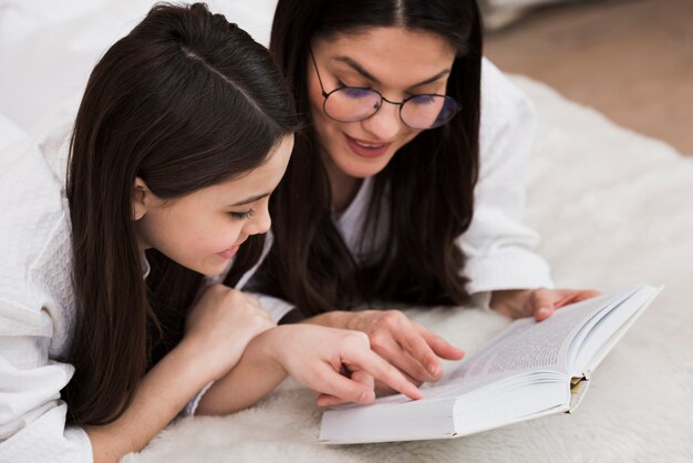Schöne Frau, die ein Buch mit jungem Mädchen liest