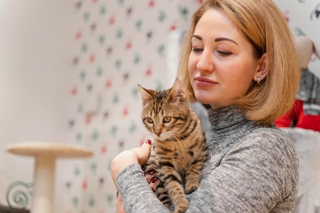 Schöne Frau, die ein Kätzchen an der Tierhandlung hält