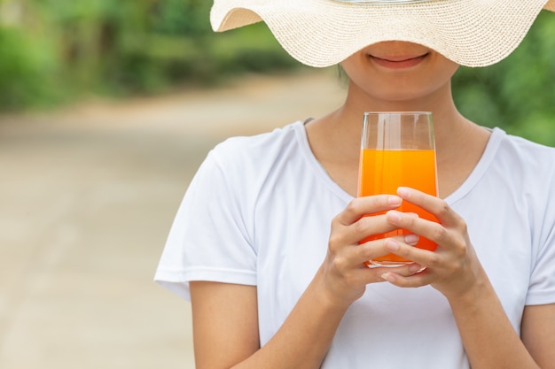 Kostenloses Foto schöne frau, die ein weißes t-shirt anhält ein glas orangensaft trägt