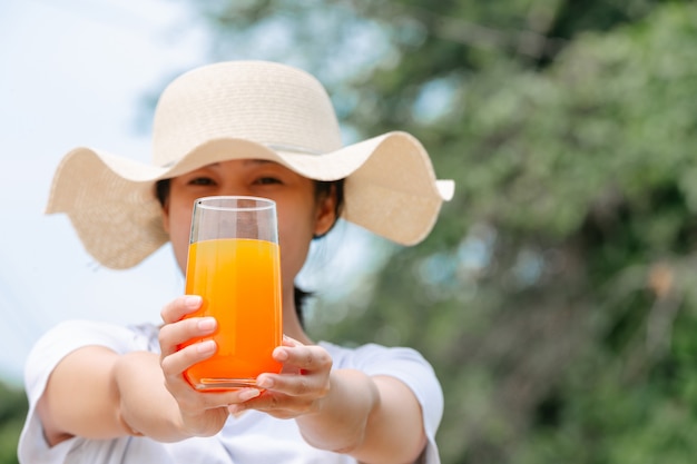 Schöne Frau, die ein weißes T-Shirt anhält ein Glas Orangensaft trägt